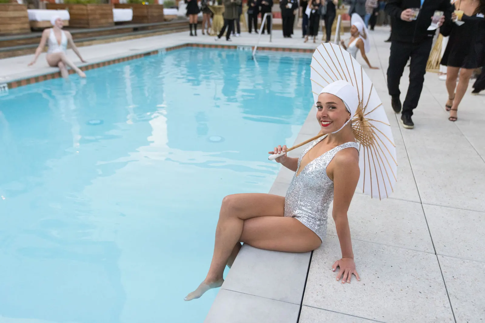 Performer in a white swimsuit sitting poolside with a parasol at the Edge 2025 rooftop event, photographed by Marquee Visuals.