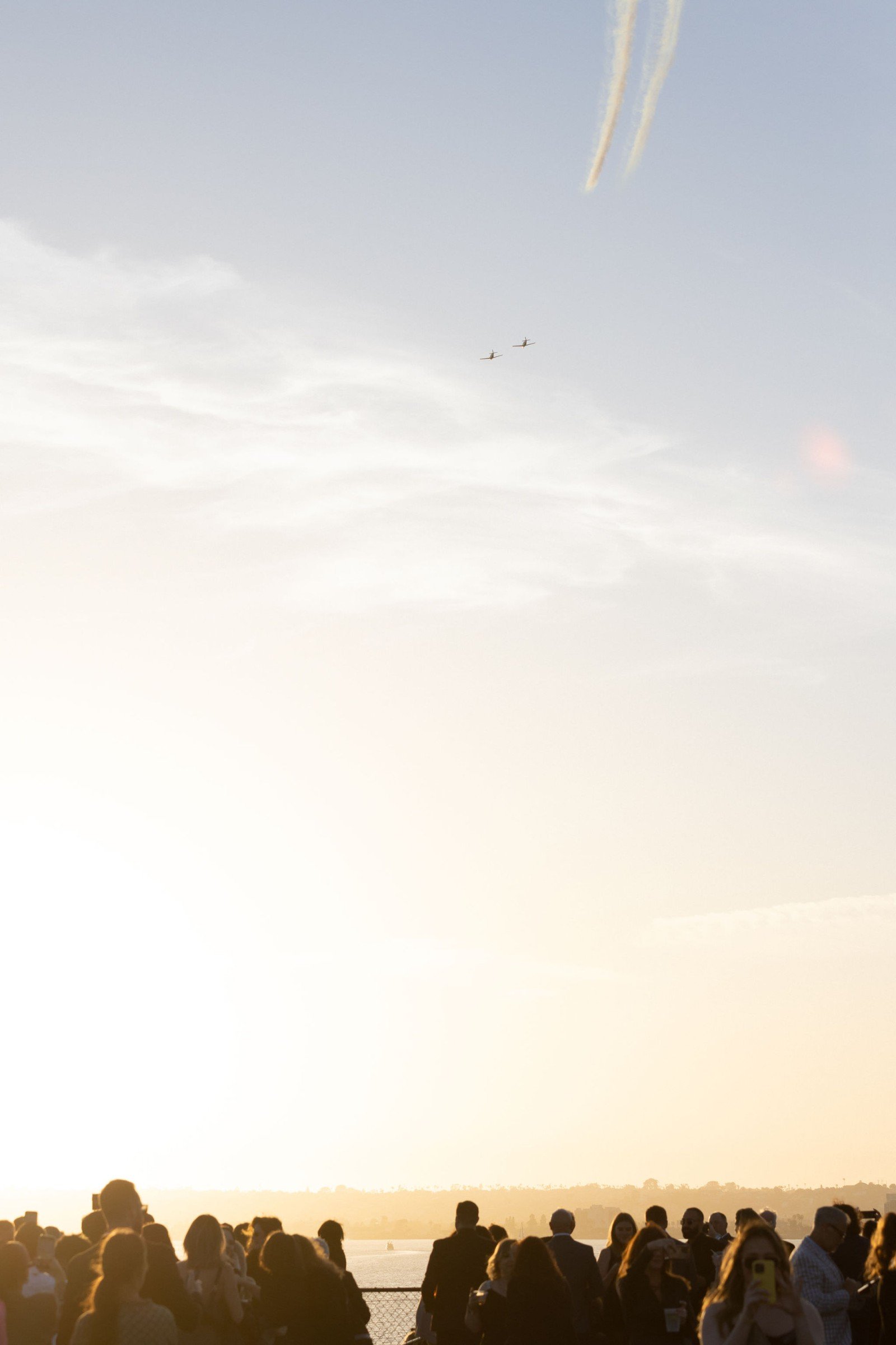 Silhouetted guests watching the sunset and planes flying overhead from an event deck, photographed by Marquee Visuals.